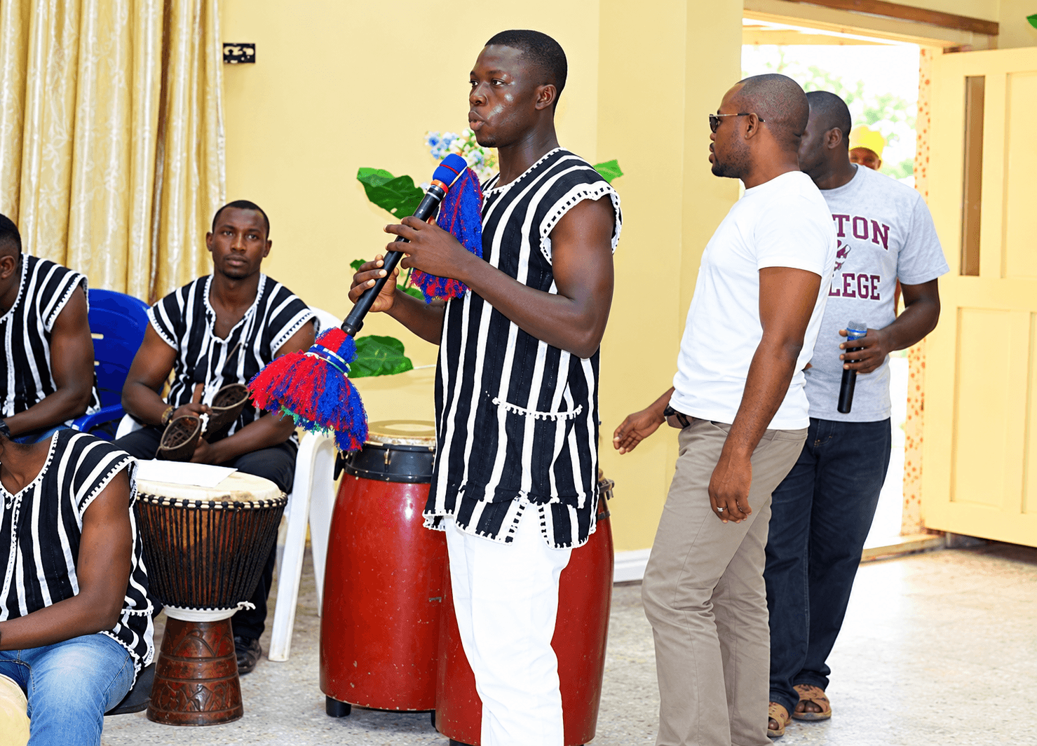 A cultural performance at a university event, with drummers in striped traditional attire.